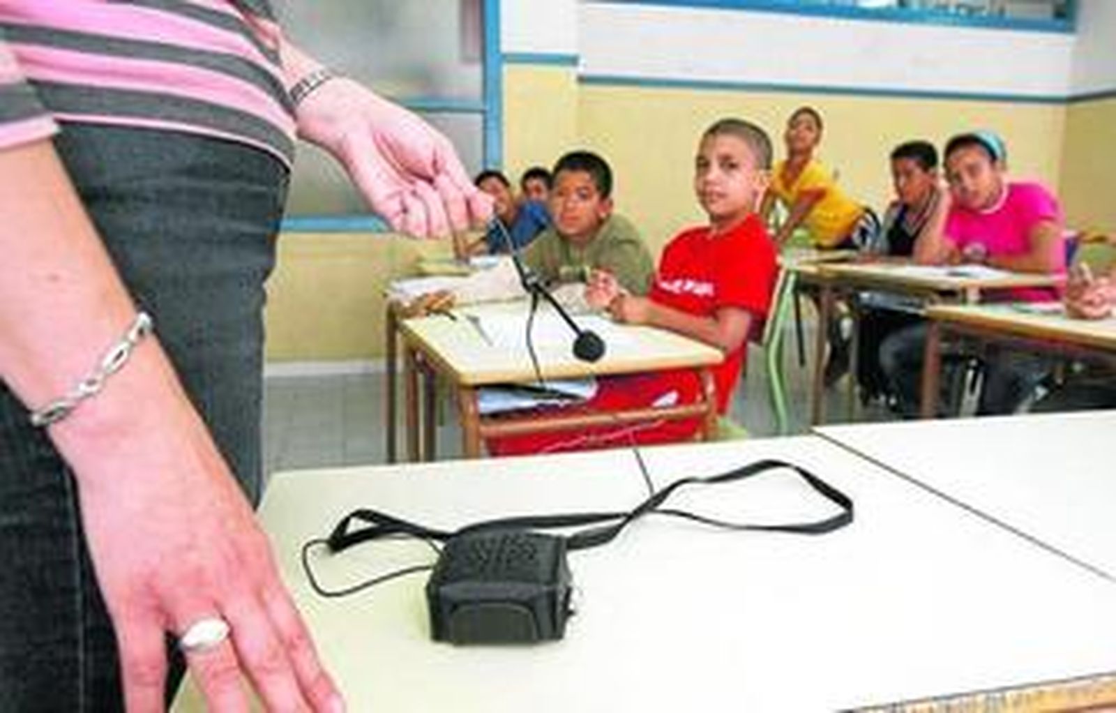 Aula de un colegio en la que la profesora utiliza un micrófono inalámbrico.