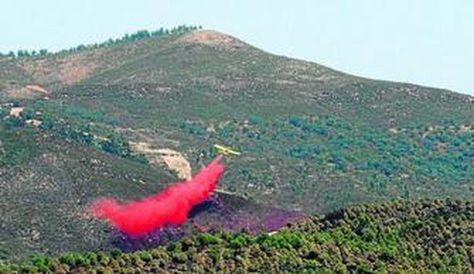 Una avioneta vierte agua con sustancias retardantes sobre uno de los últimos focos activos del incendio que arrasó 400 hectáreas en Mina Concepción.