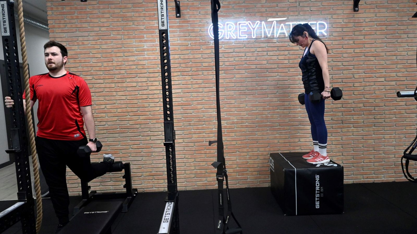 Dos personas hacen diferentes ejercicios con pesas en Grey Matter.