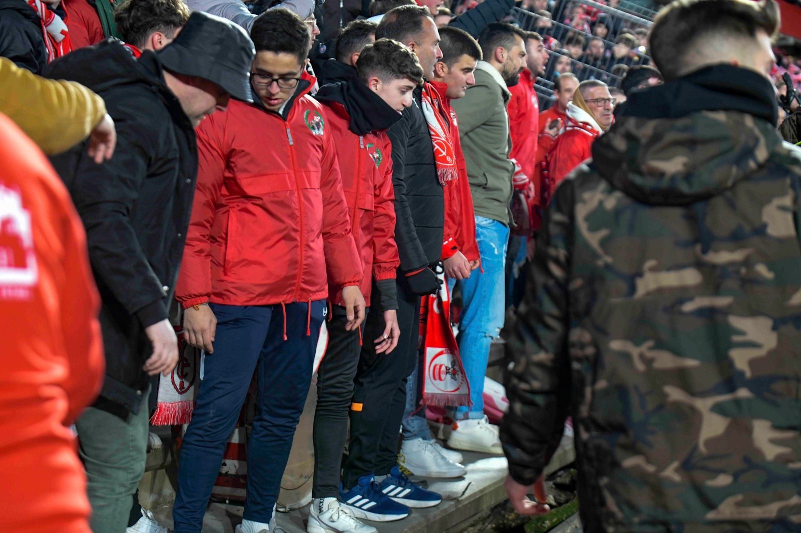Los aficionados del Granada CF mira la valla tras la caída de la misma.