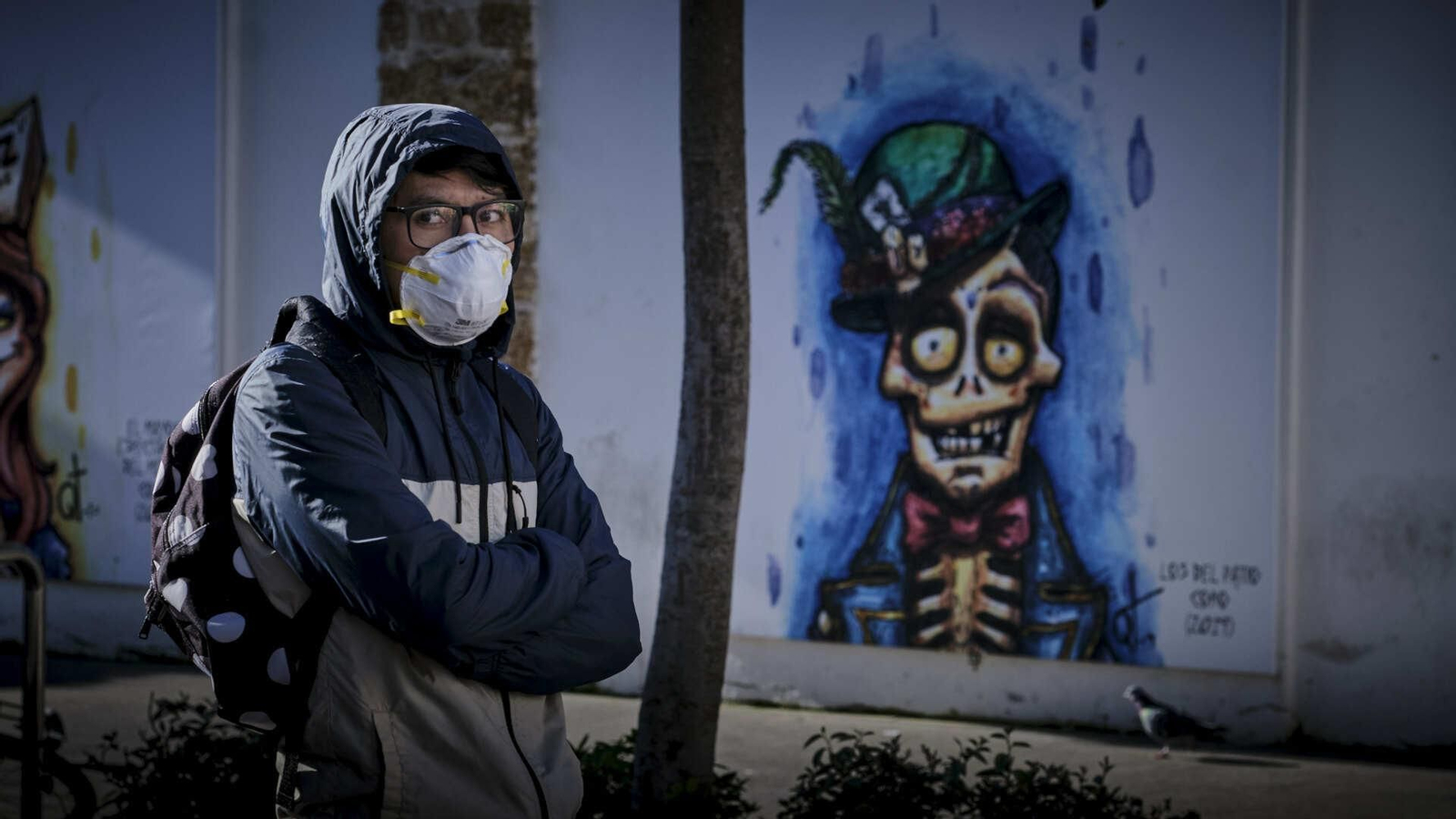 Una persona con mascarilla guarda cola para entrar en un supermercado frente a la exposición de Carnaval que circunda el Mercado Central