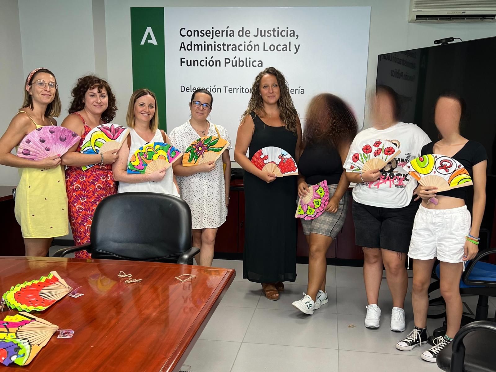 Las menores y su tutora enseñan a la delegada las piezas que han salido del taller de Pintura Artística