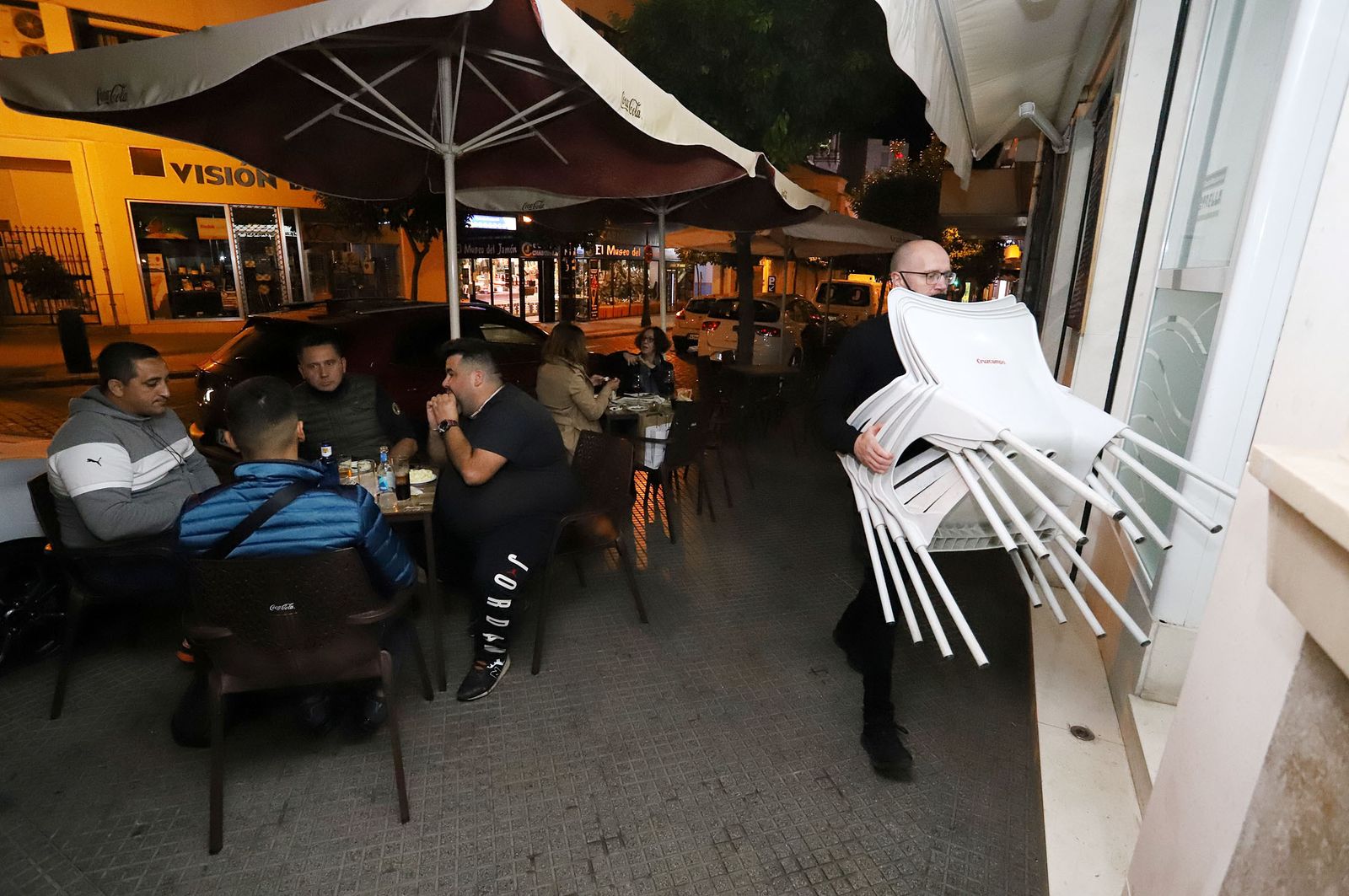 Un camarero recoge las sillas en un bar de Huelva