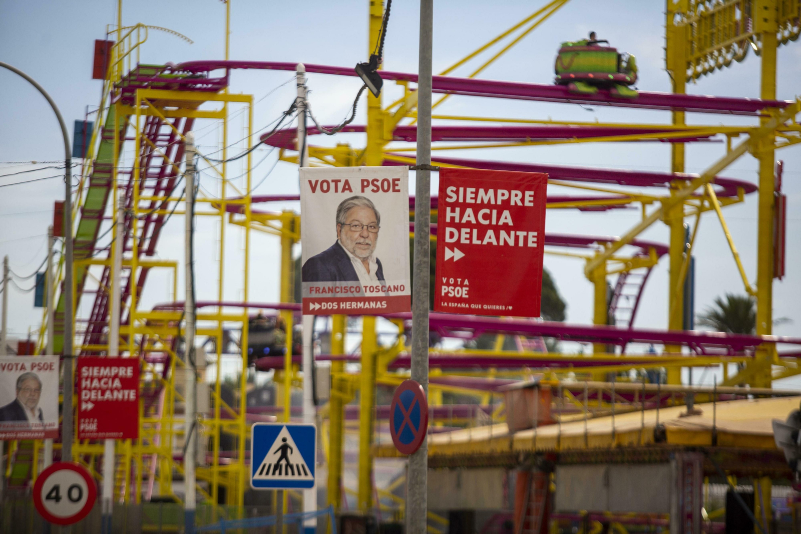 Carteles electorales de Toscano, con la perspectiva de la montaña rusa de la Feria, que se celebró hasta el domingo en el municipio.