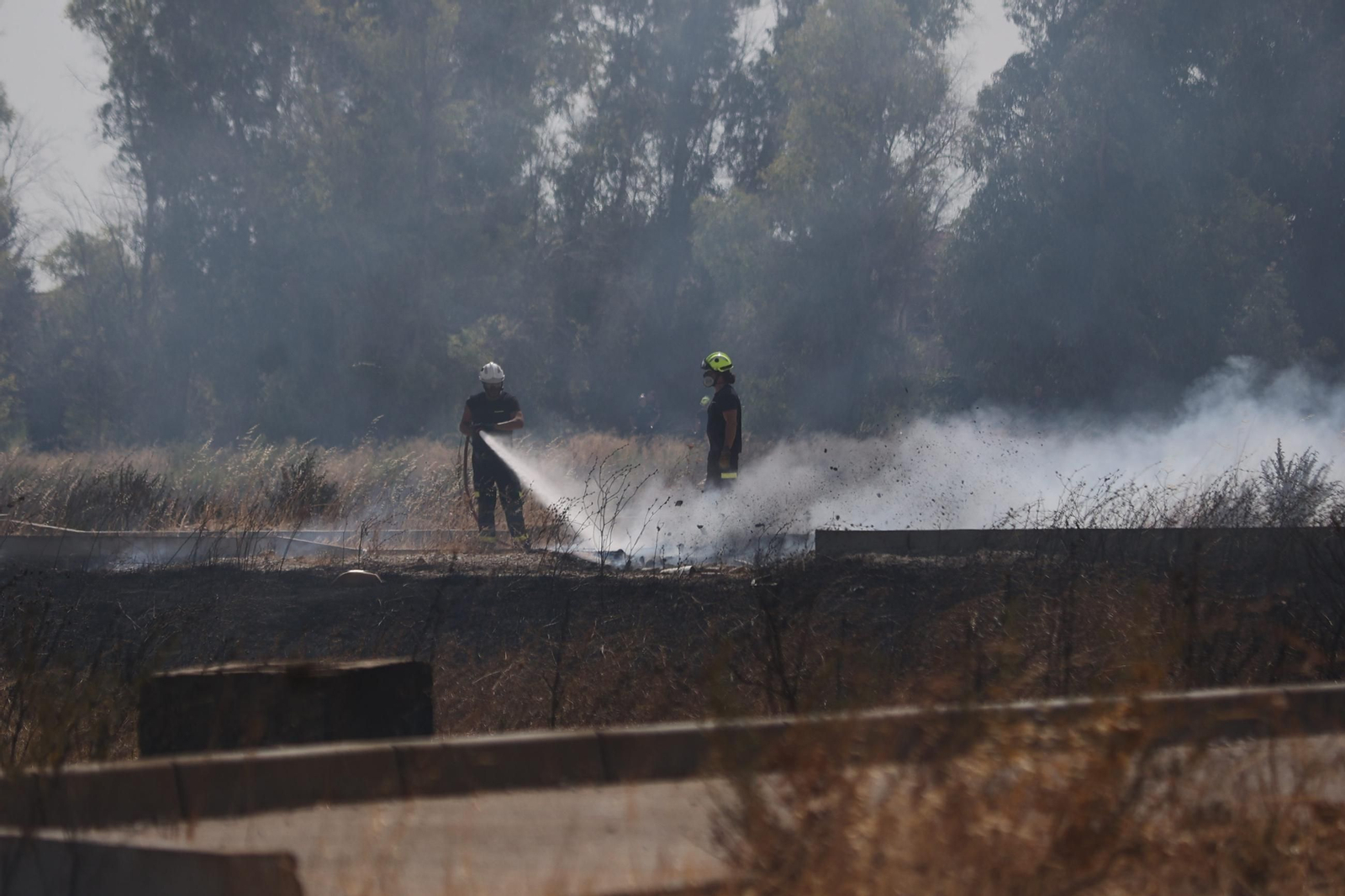 Dos bomberos, tratando de controlar el fuego originado cerca de La Marquesa.