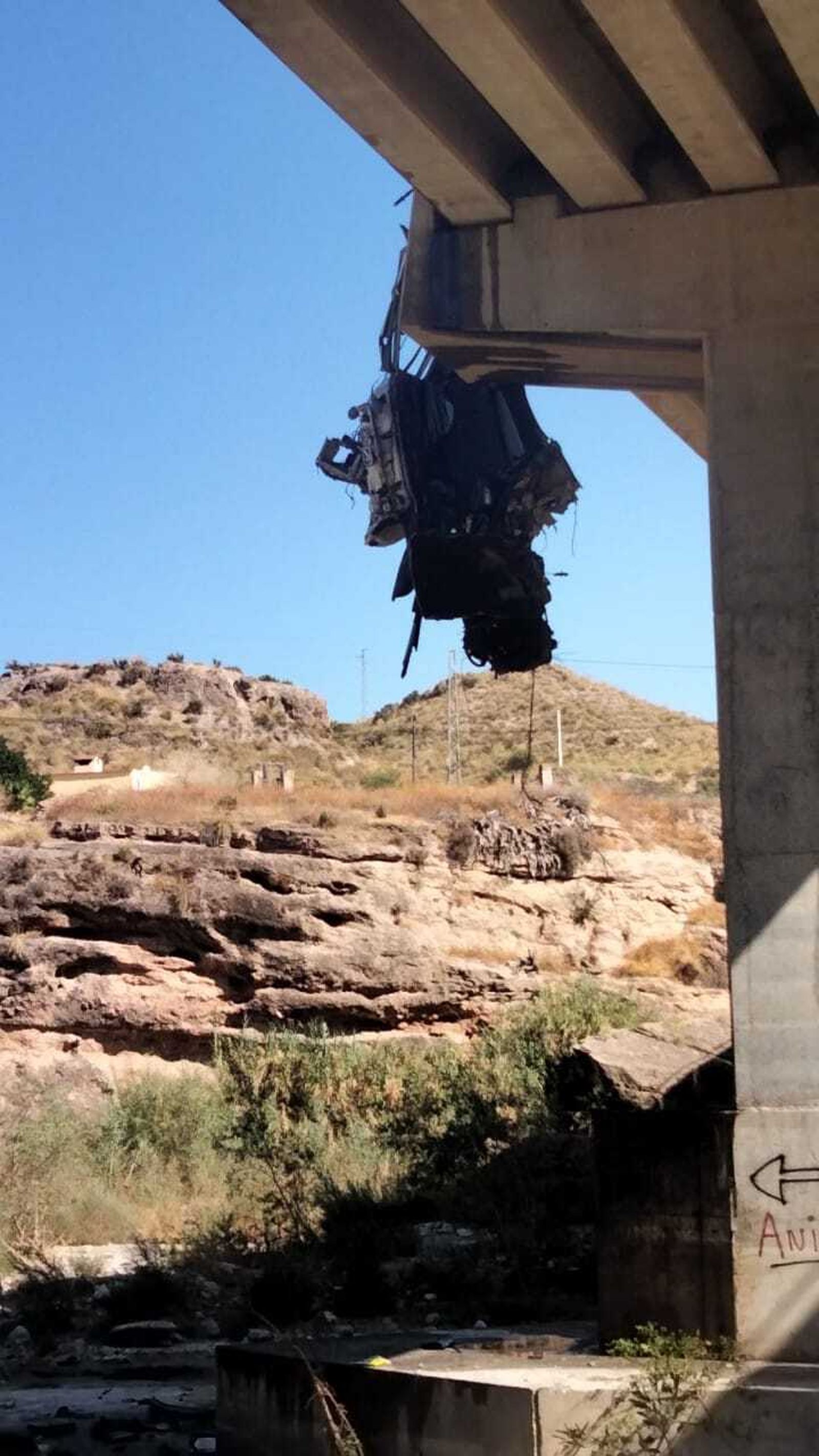 El camión-bañera, destrozado colgando hacia el río.