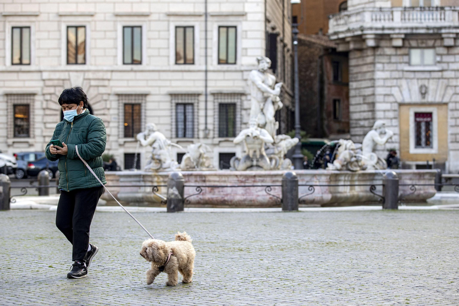 Una mujer pasea a su perro por el centro de Roma.