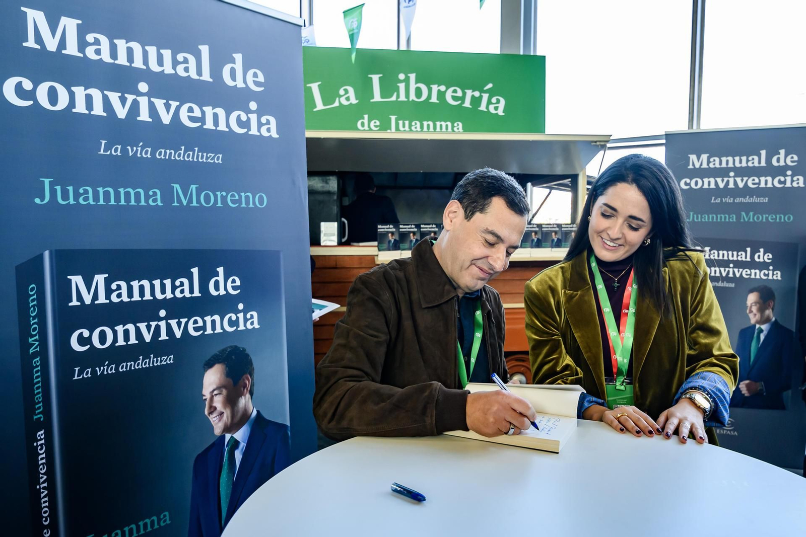 Juanma Moreno firma ejemplares en el XVII Congreso Regional del PP en Sevilla.