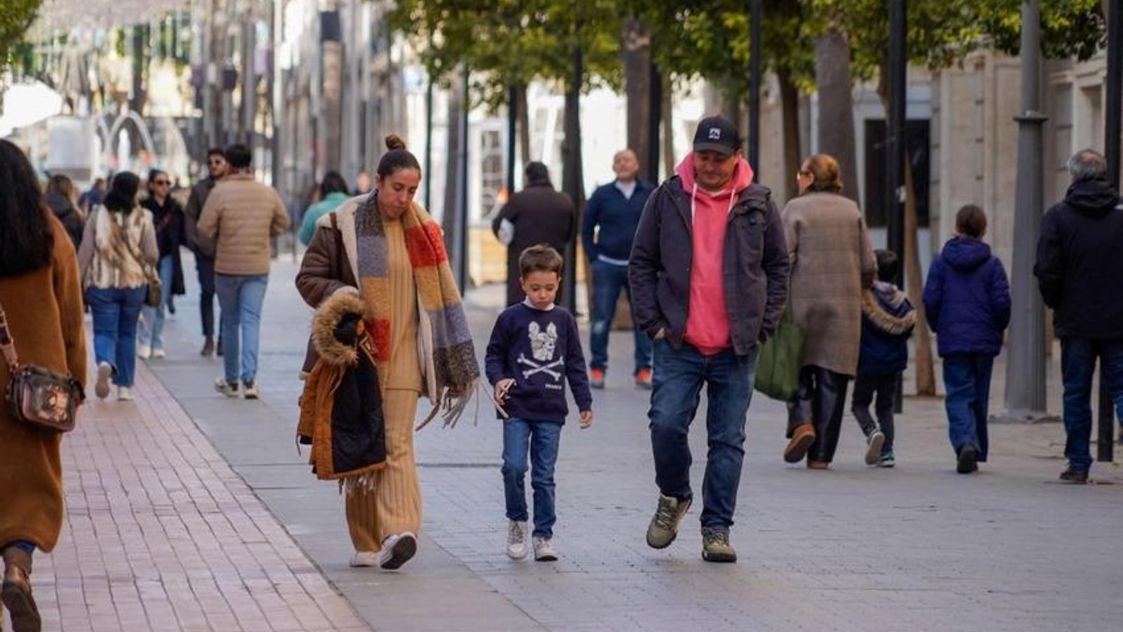 Personas pasean abrigados por el frío por las calles del centro de Huelva.