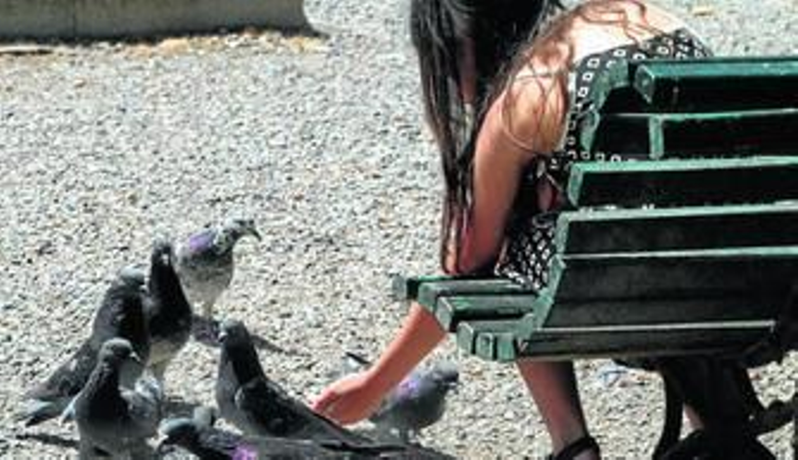 Una mujer da de comer a las palomas en una plaza.