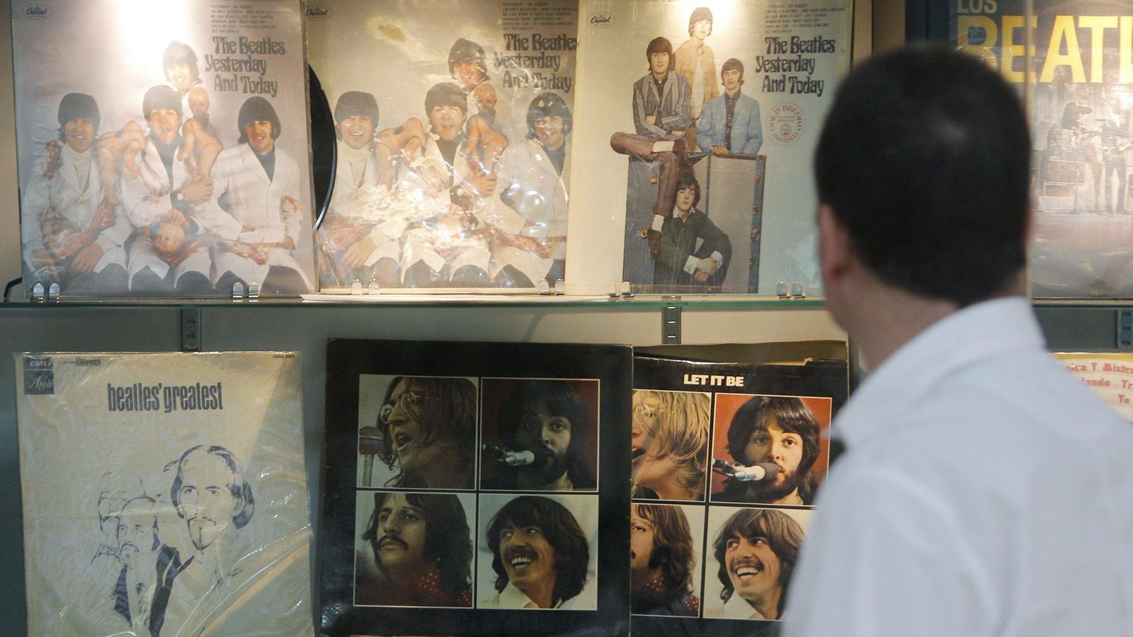 Un aficionado observa varios discos de Los Beatles en una exposición en Granada.