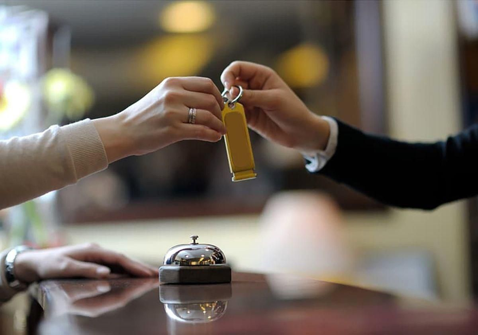 Un recepcionista de un hotel entrega en mano la llave a un turista.