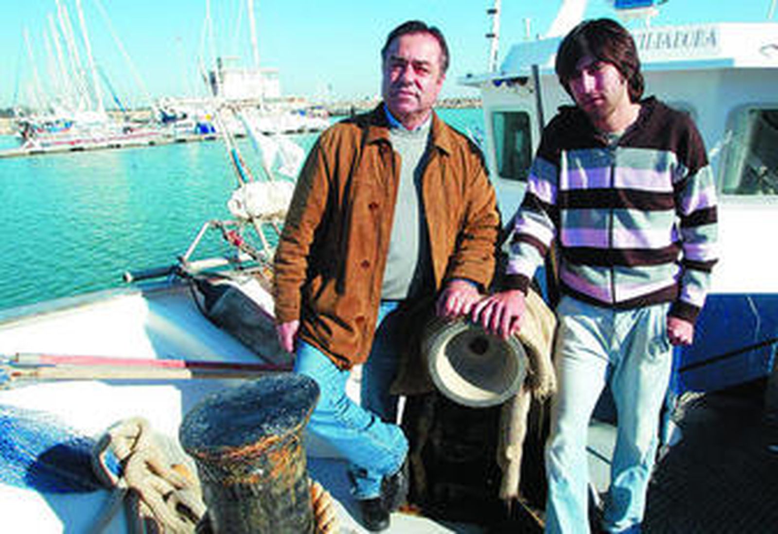 Manolo y Lolo posan en su otra 'casa', la proa de un barco en el muelle de Rota, donde comparten la pasión por el mar.