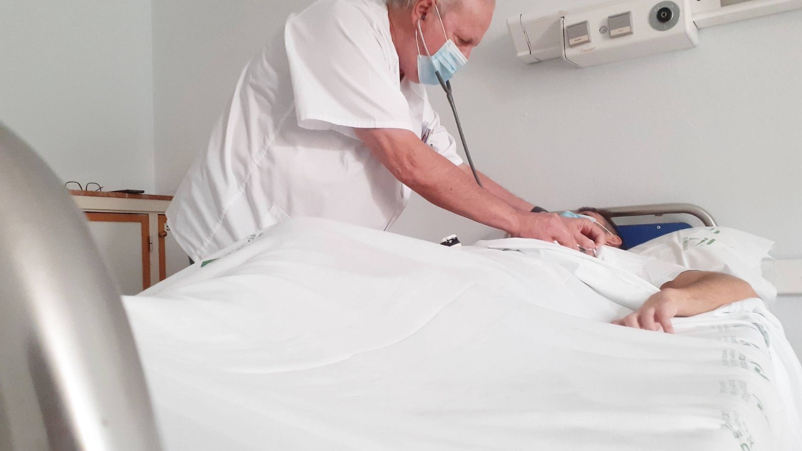 E doctor Ruiz, junto a un paciente en la planta de hospitalización.