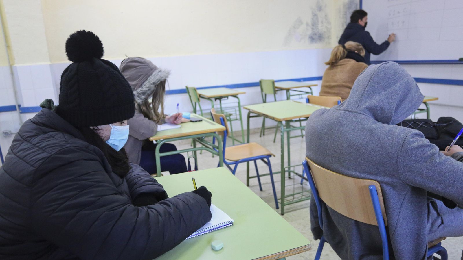 Alumnos protegidos del frío con gorros, bufandas y abrigos.