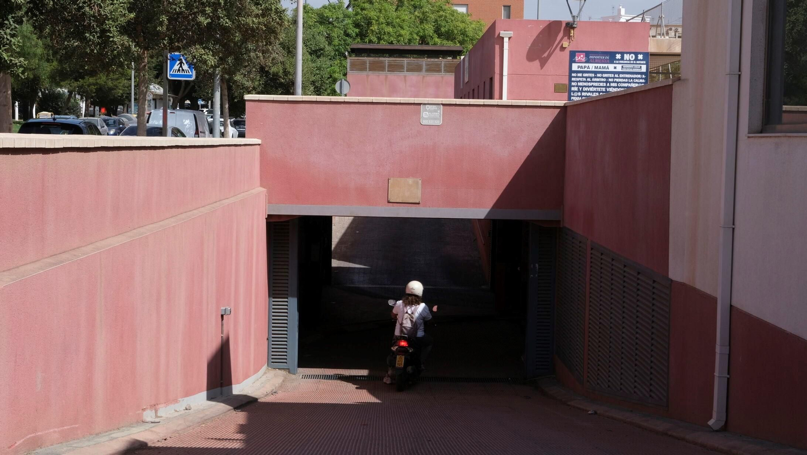 Una mujer accede en motocicleta al parking de Los Molinos.