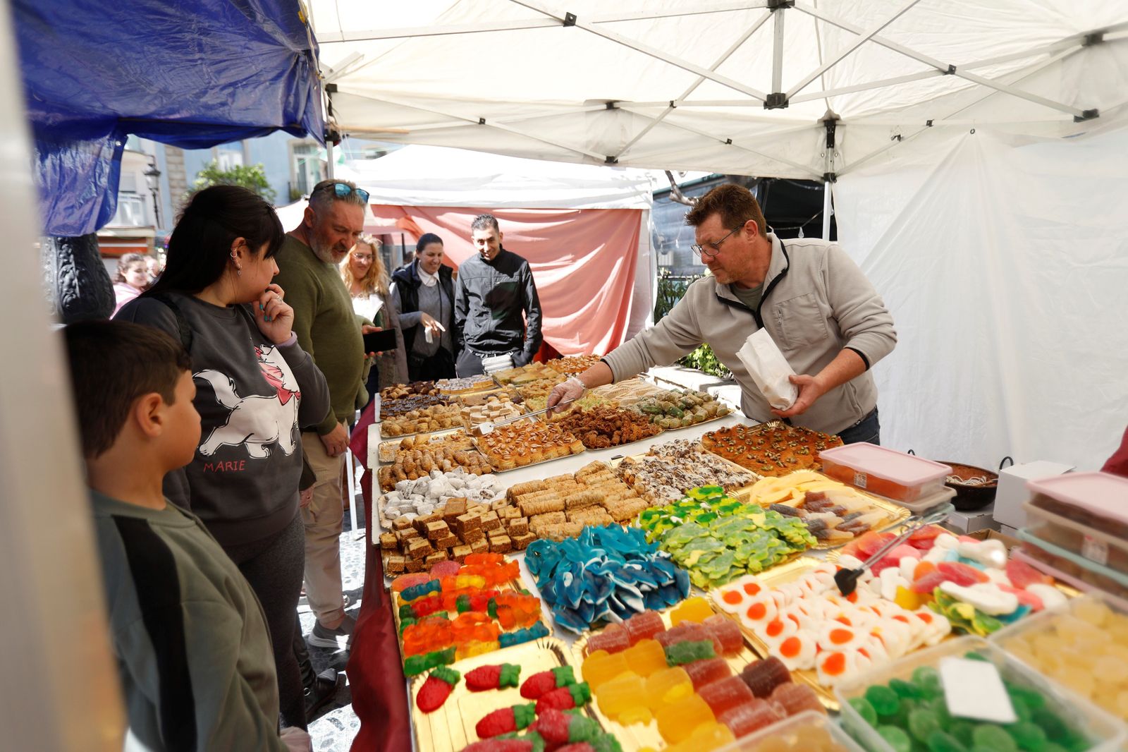 Un tendero despacha dulces en el mercado de productos andaluces de La Línea.