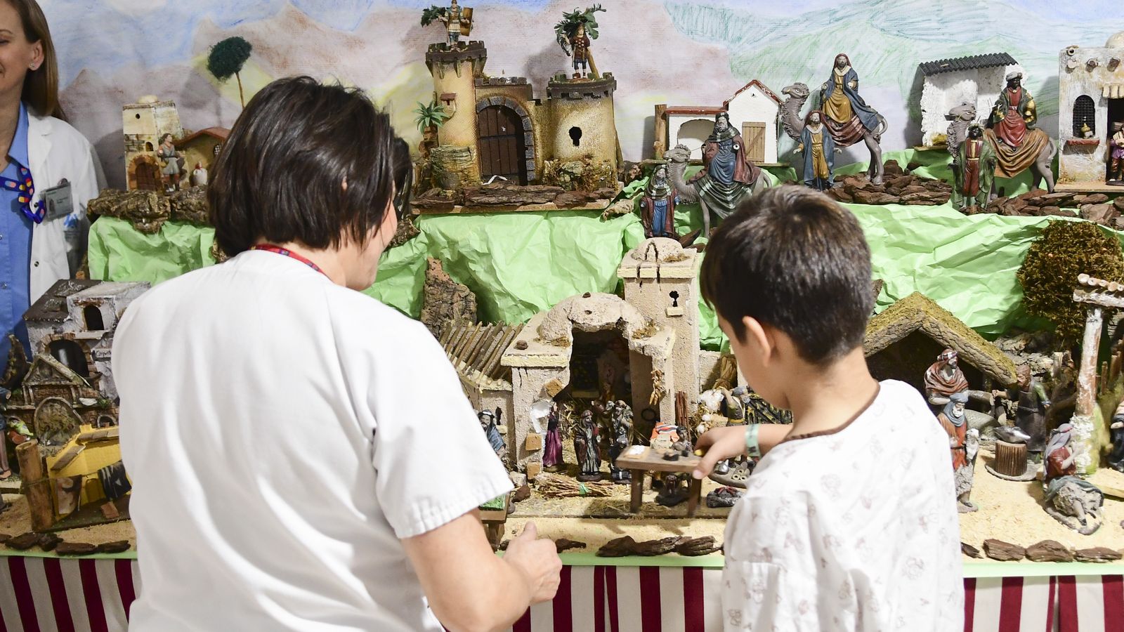 Un niño coloca una figura en un nacimiento en el hospital