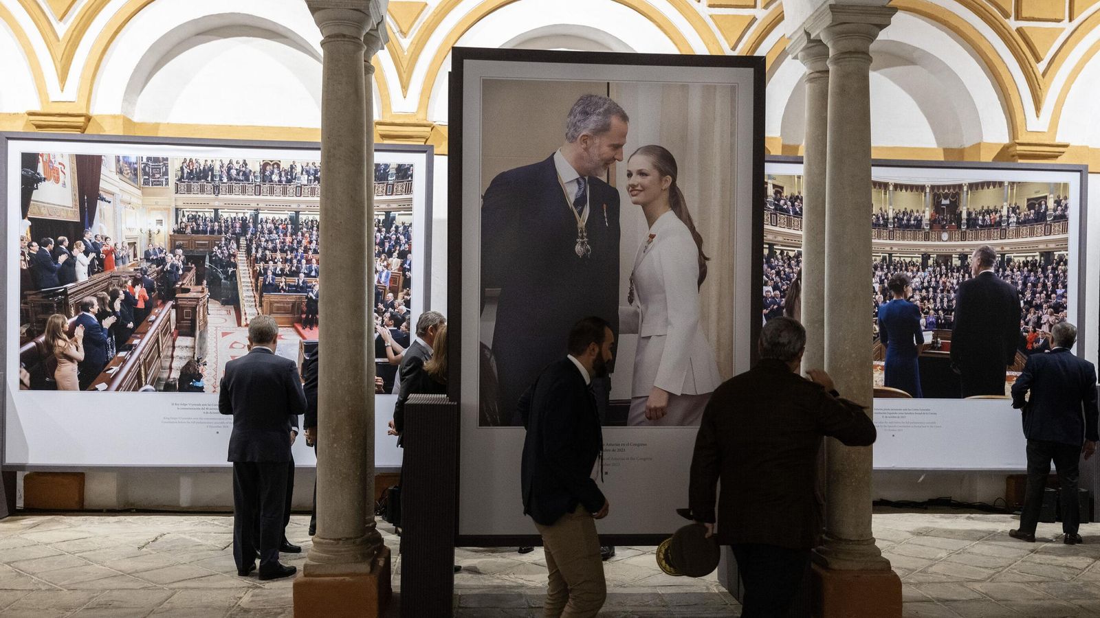 Varias personas delante de la fotografía en la que la Princesa de Asturias firma el Libro de Honor del Congreso tras el acto en que juró la Constitución.