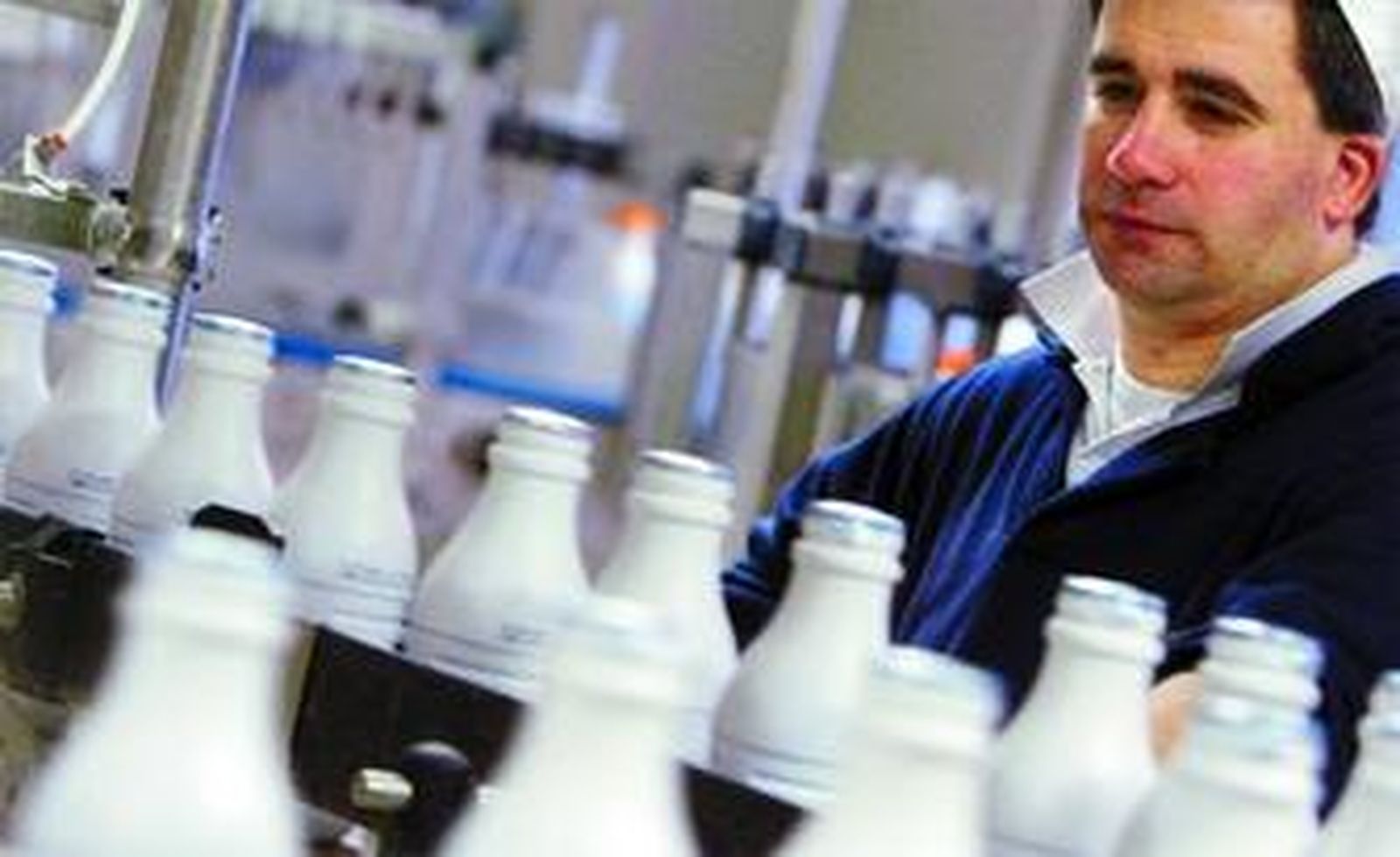 Un operario vigila la producción en una planta de embasado y distribución de leche.