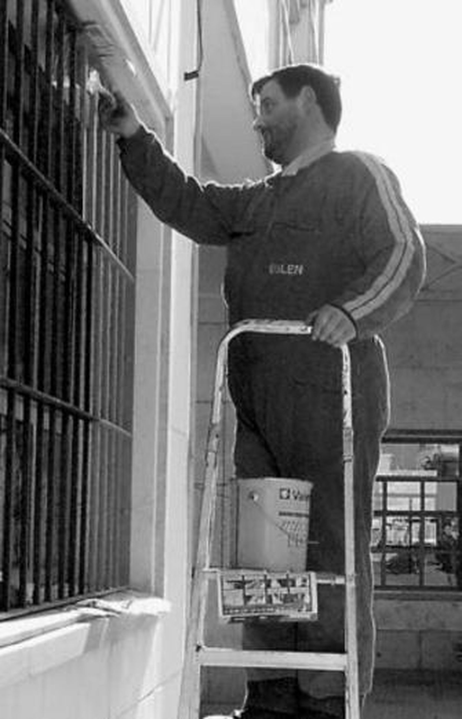Un trabajador pinta las rejas de una ventana.