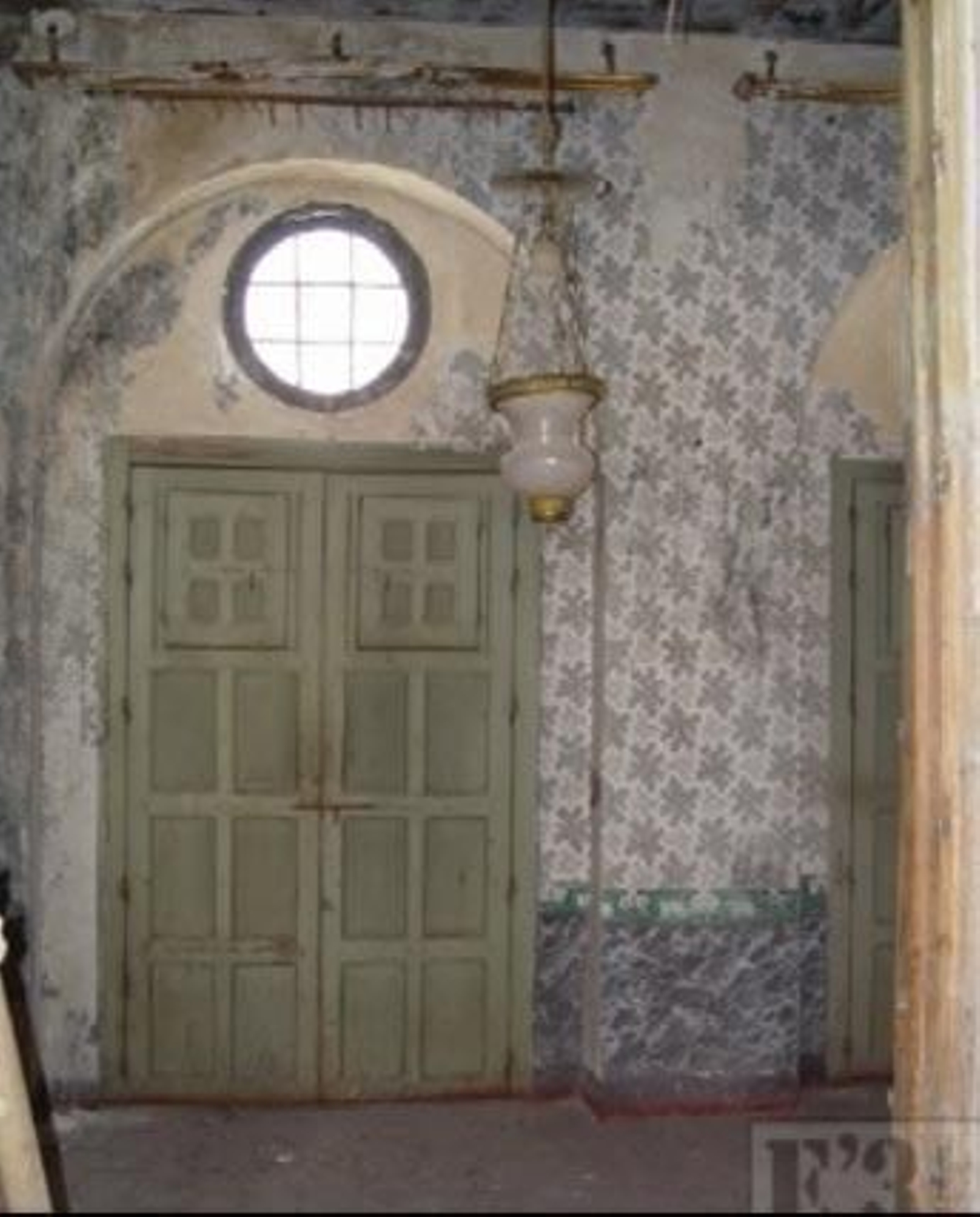 Una puerta con una ventana arriba, y las paredes gastadas.