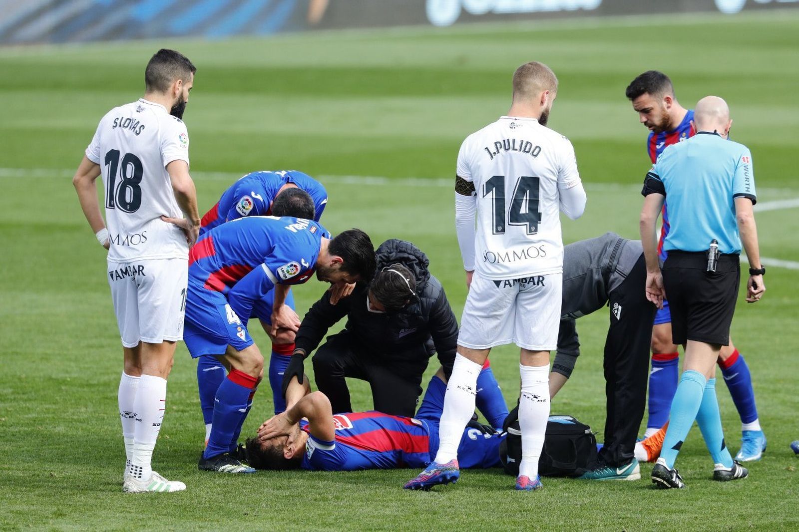 Pedro Bigas es atendido en el césped mientras se tapa la cara por el dolor.