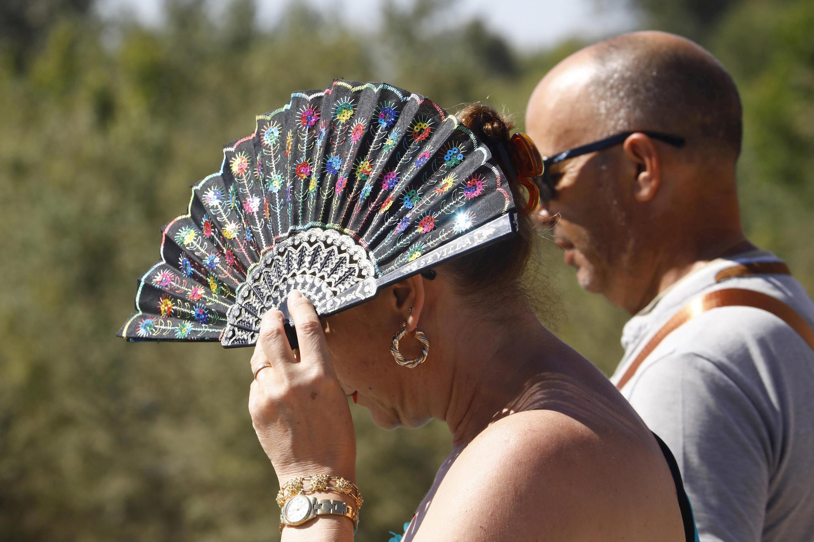 Una mujer se protege del calor con un abanico.