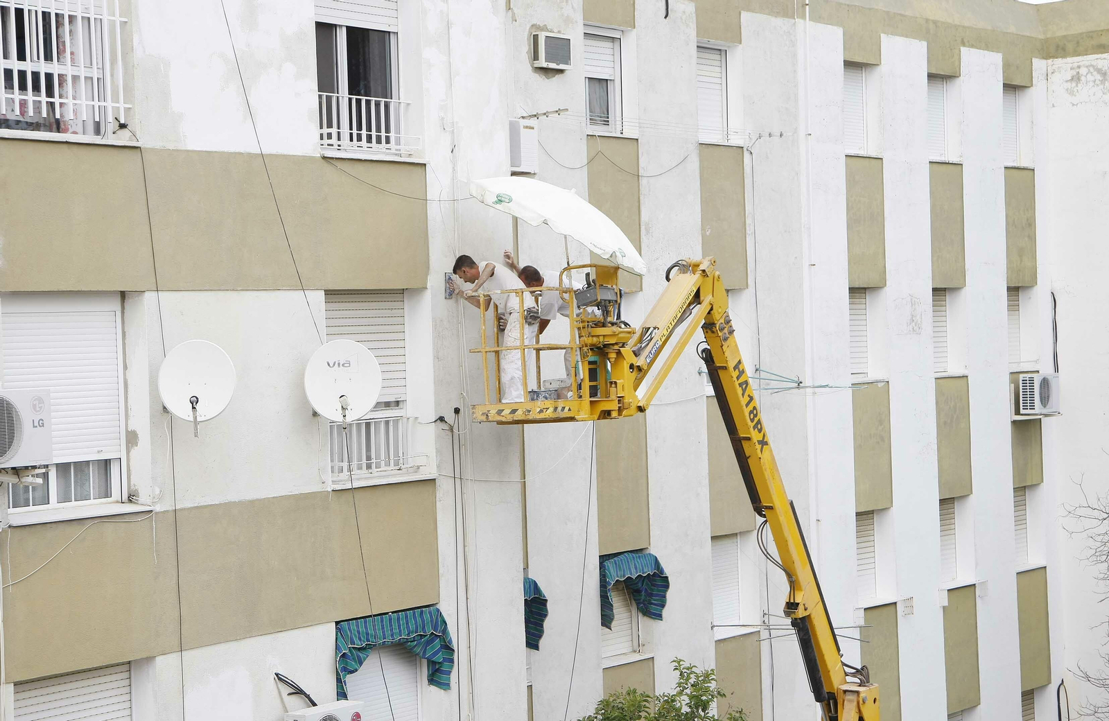 Dos operarios adecentando una fachada.