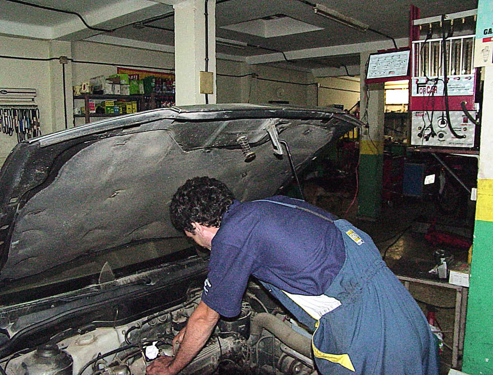 Un mecánico realiza trabajos en un coche en un taller.