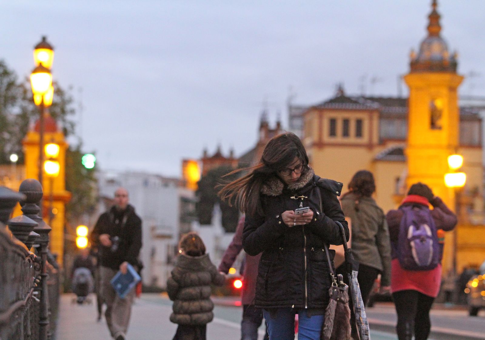 Paseantes abrigados por el puente de Triana.
