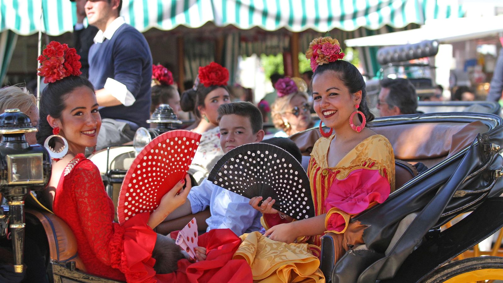 Dos jóvenes en coche de caballo vestidas de flamenca.