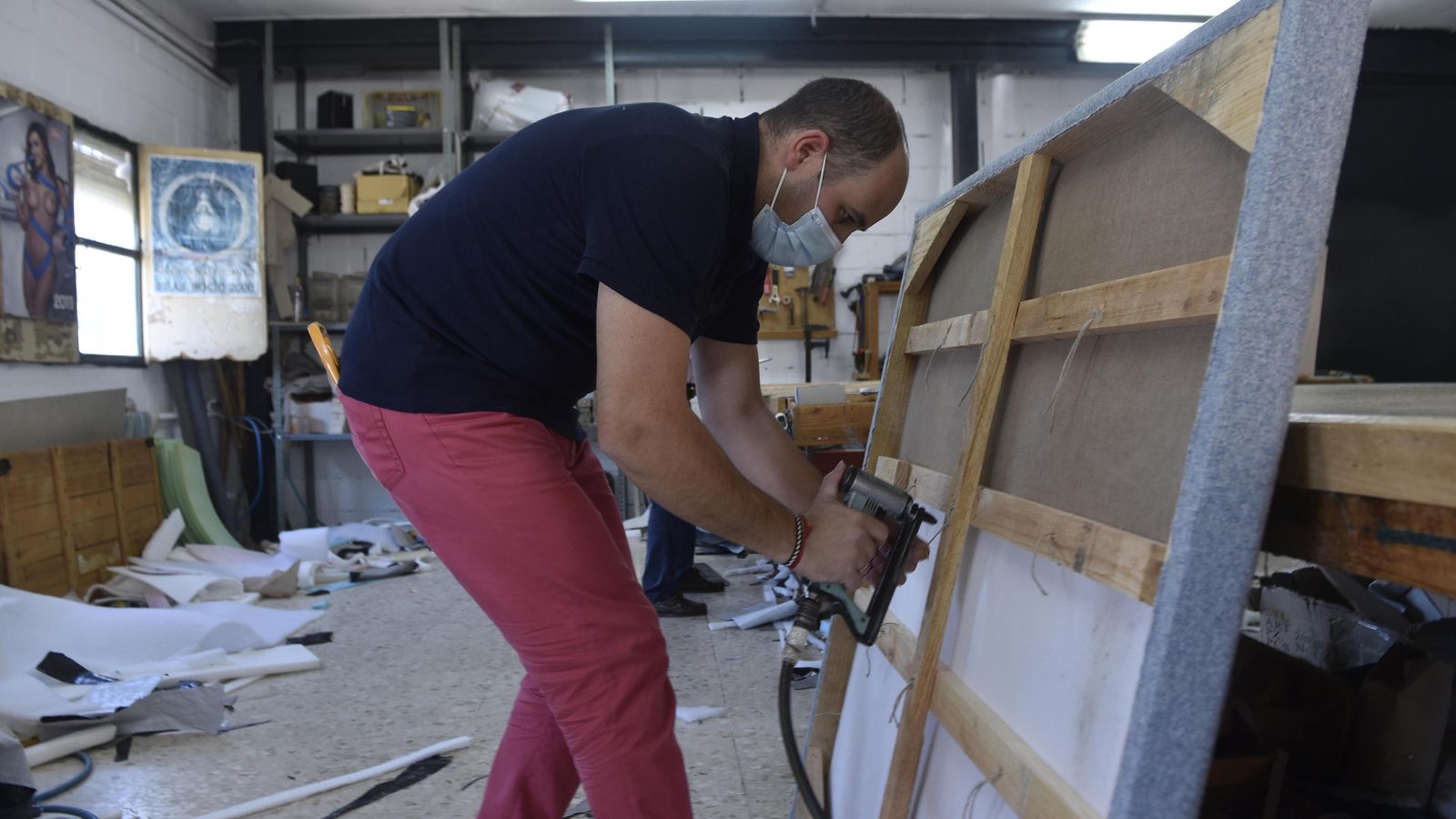 Un tapicero en prepara un armazón, en Pilas.