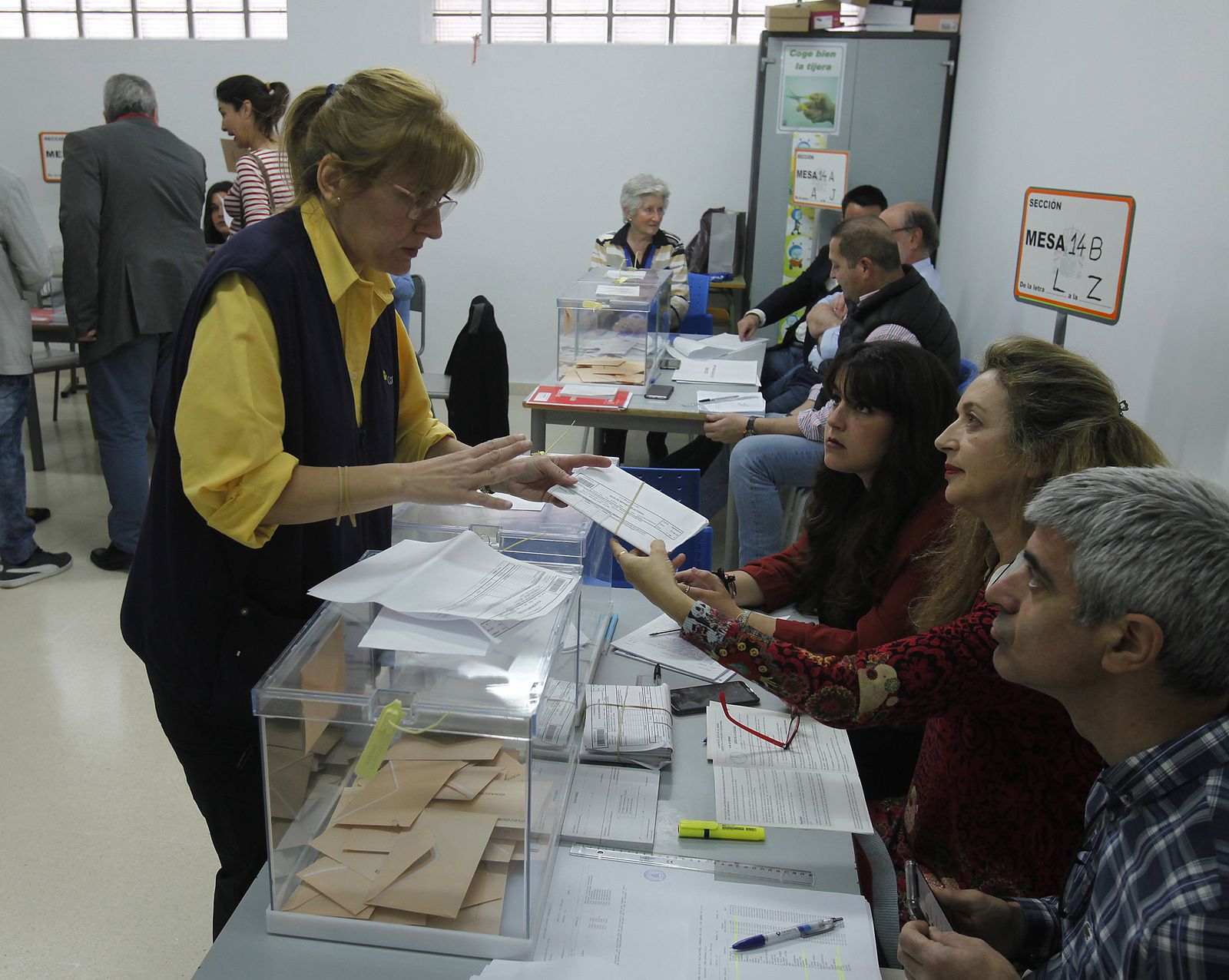 Una funcionaria de Correos entrega en una mesa electoral el voto por correo