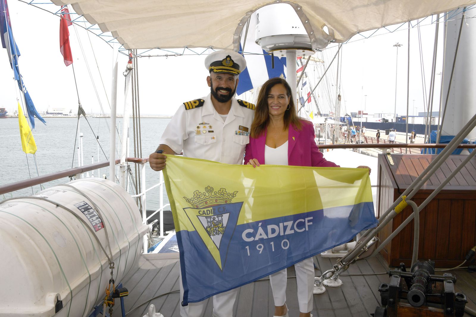 La consejera Montserrat Medina posa en uno de los barcos con una bandera de equipo.