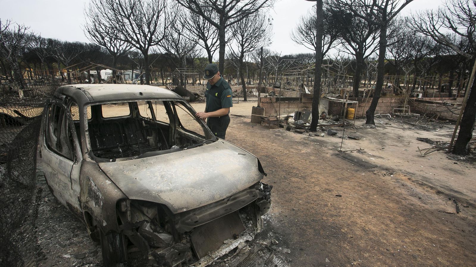 Un guardia civil inspecciona un coche calcinado en el camping Doñana en 2017.