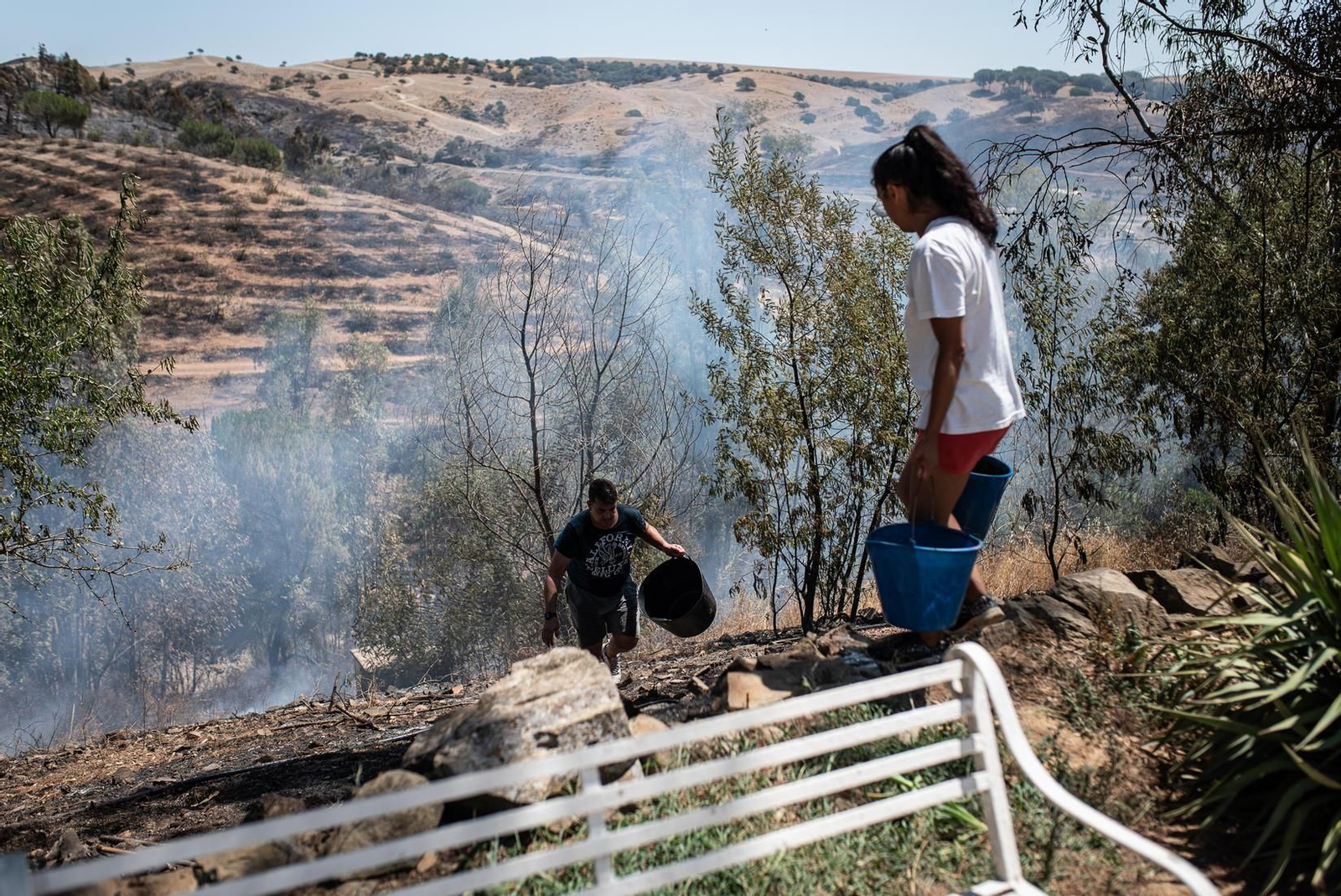 Miguel y su mujer refrescan los alrededores de la casa para que las llamas no vuelvan.