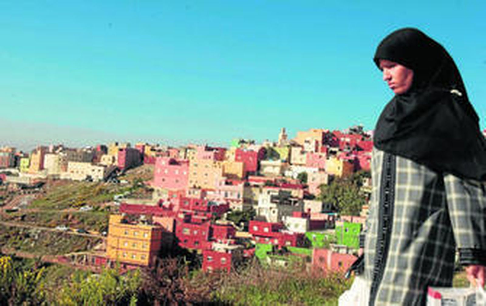 Una mujer musulmana pasea por los alrededores del hospital de Ceuta, con el bario del Príncipe Alfonso al fondo.