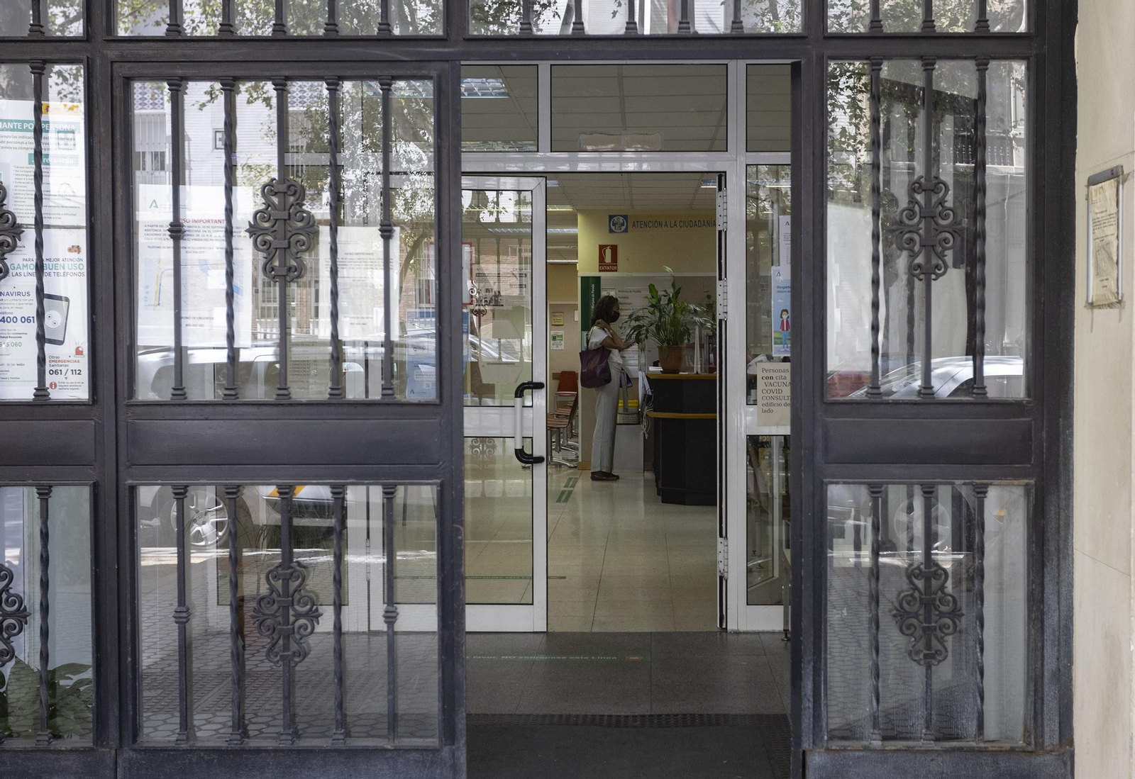 Una mujer, al fondo, ante el mostrador de recepción del centro de salud de Marqués de Paradas, en la capital.