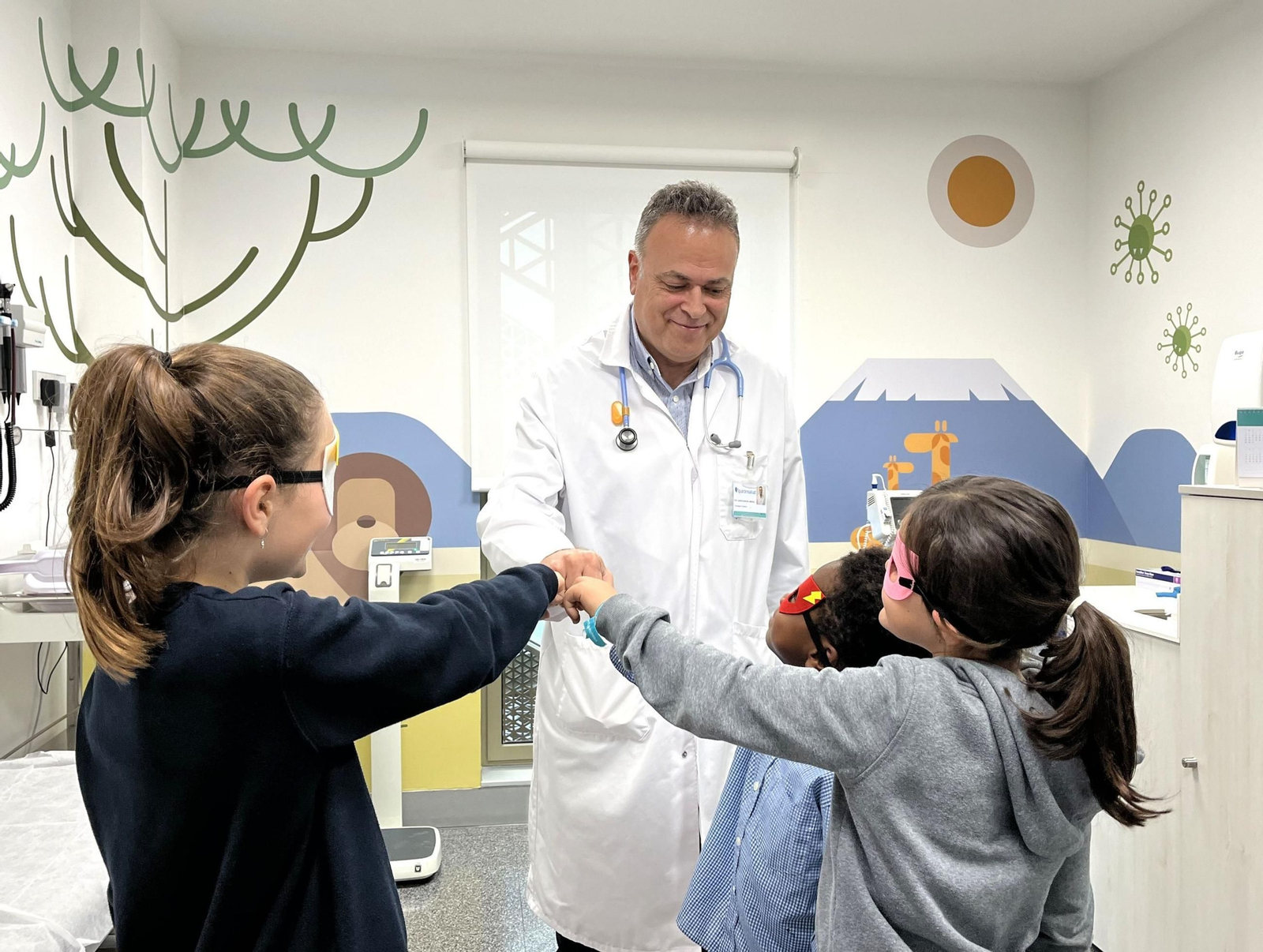 Un pediatra conversa con varios niños en la consulta.