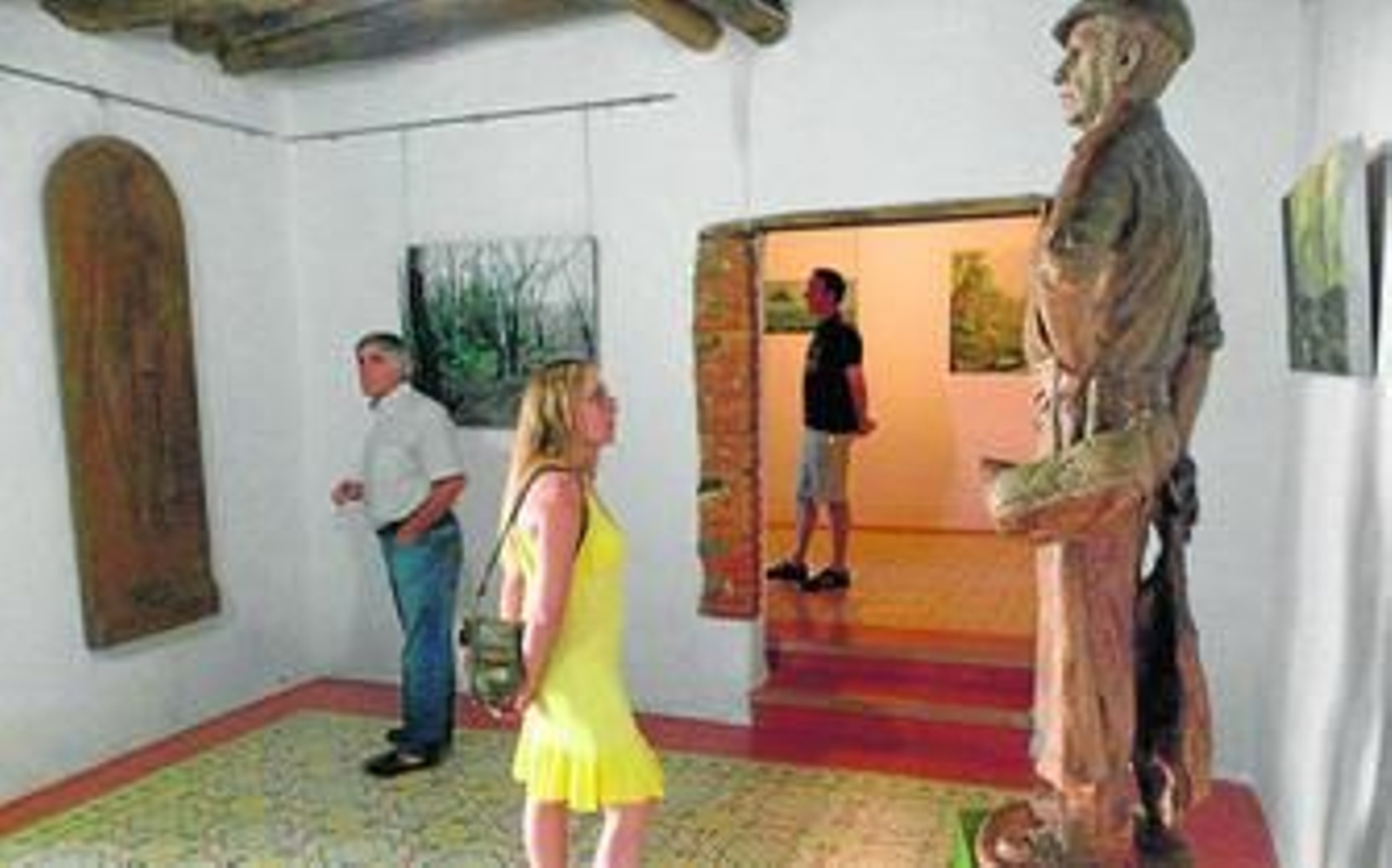 Visitantes observan las obras de la muestra 'Todo por la cultura', en Linares de la Sierra.