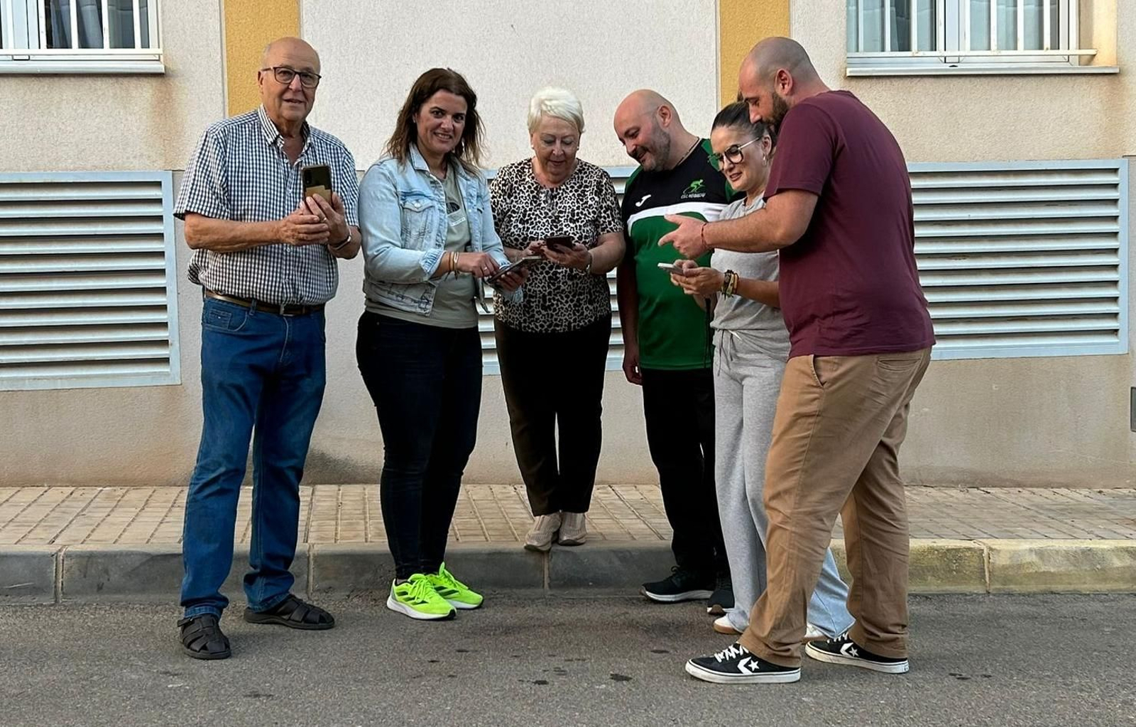 Noelia Damián, con concejales y vecinos mirando el móvil.