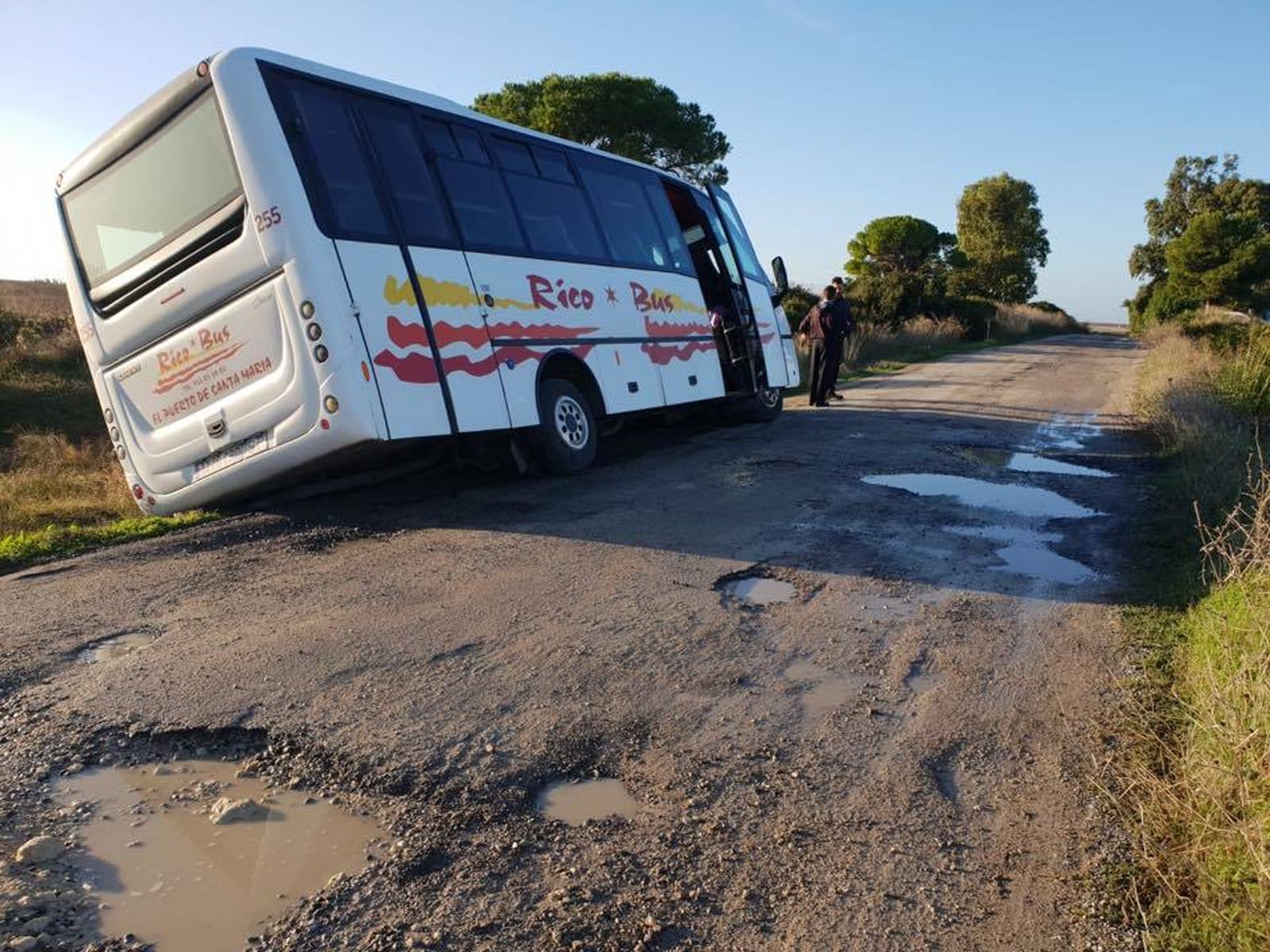 El autobús escolar que circula diariamente por el Camino del Abulagar, atrapado en la cuneta.