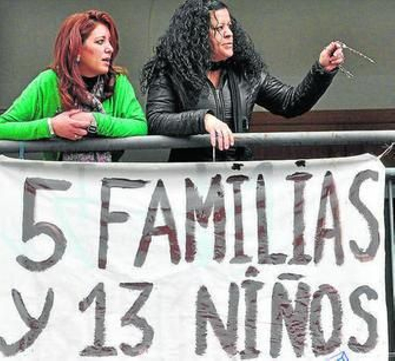 Dos ocupantes tras una pancarta colgada en la fachada del bloque.