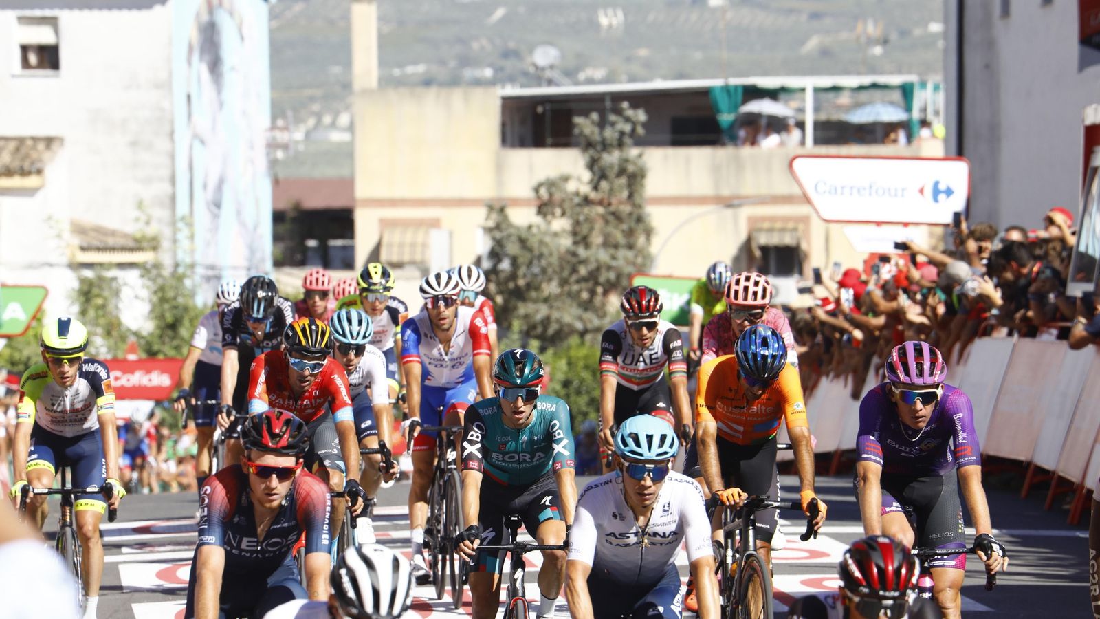 Llegada a la meta de varios ciclistas rodeados de aficionados.