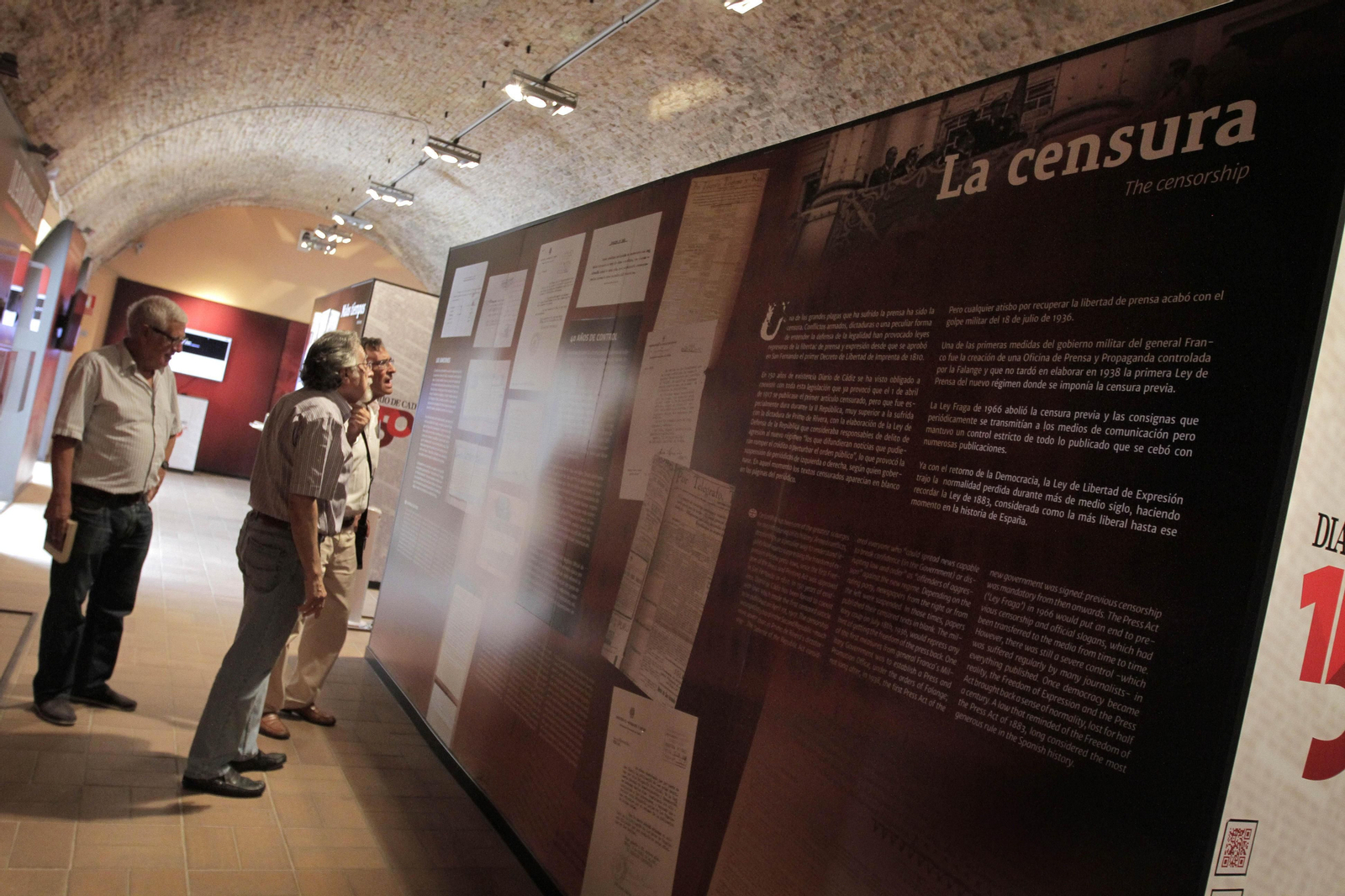 Visitantes de la exposición 'Nuestra historia es Cádiz' observando el panel de la censura en los medios.