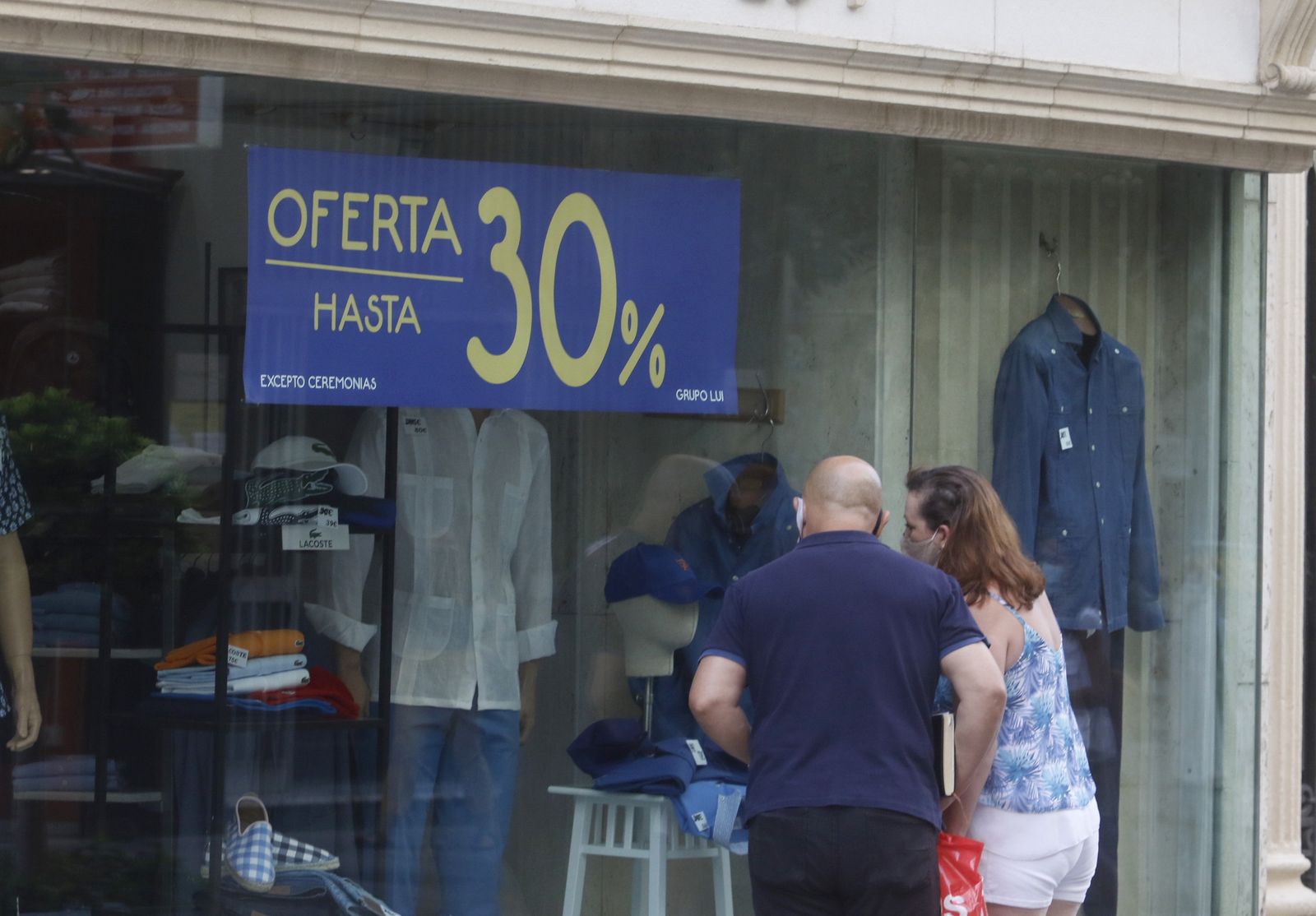 Una pareja de cordobeses mira el escaparate de una tienda en rebajas.