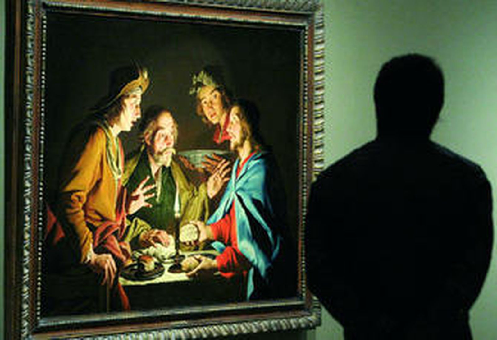 Un hombre observa el cuadro 'La cena de Emaus' (1633), de Matthias Stom.