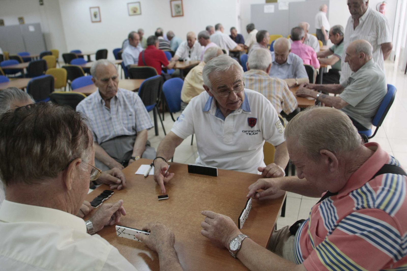 Un grupo de pensionistas juegan al dominó.