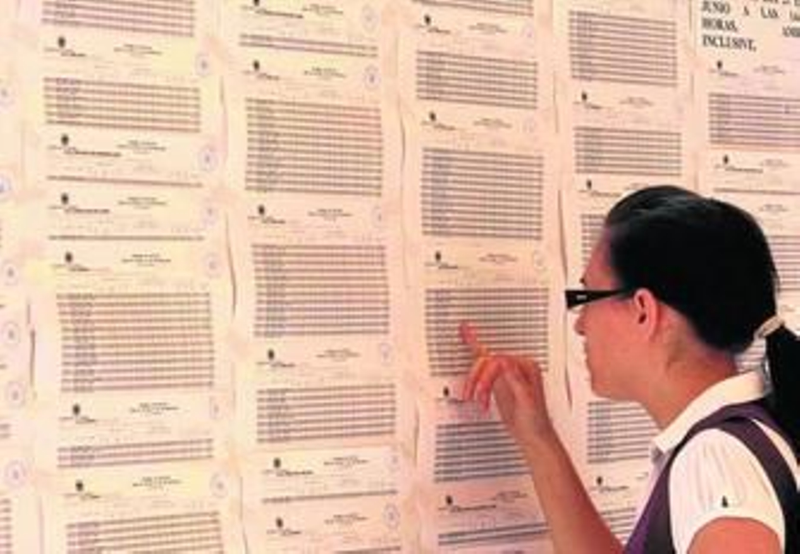 Una alumna comprueba calificaciones en el tablón de un centro universitario.